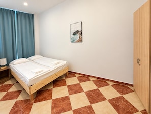 A bedroom with a bed, a nightstand, a wardrobe, and a painting on the wall. - Vienna Living 1BR for Extended Stays (Wien)