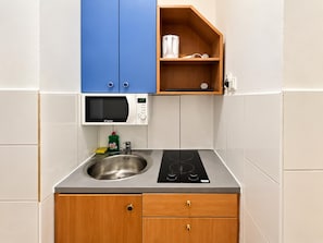 A compact kitchen with a microwave, a sink, and a built-in stove. - Vienna Living 1BR for Extended Stays (Wien)