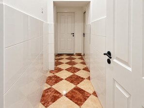 A hallway with white walls and a checkered floor pattern. - Vienna Living 1BR for Extended Stays (Wien)