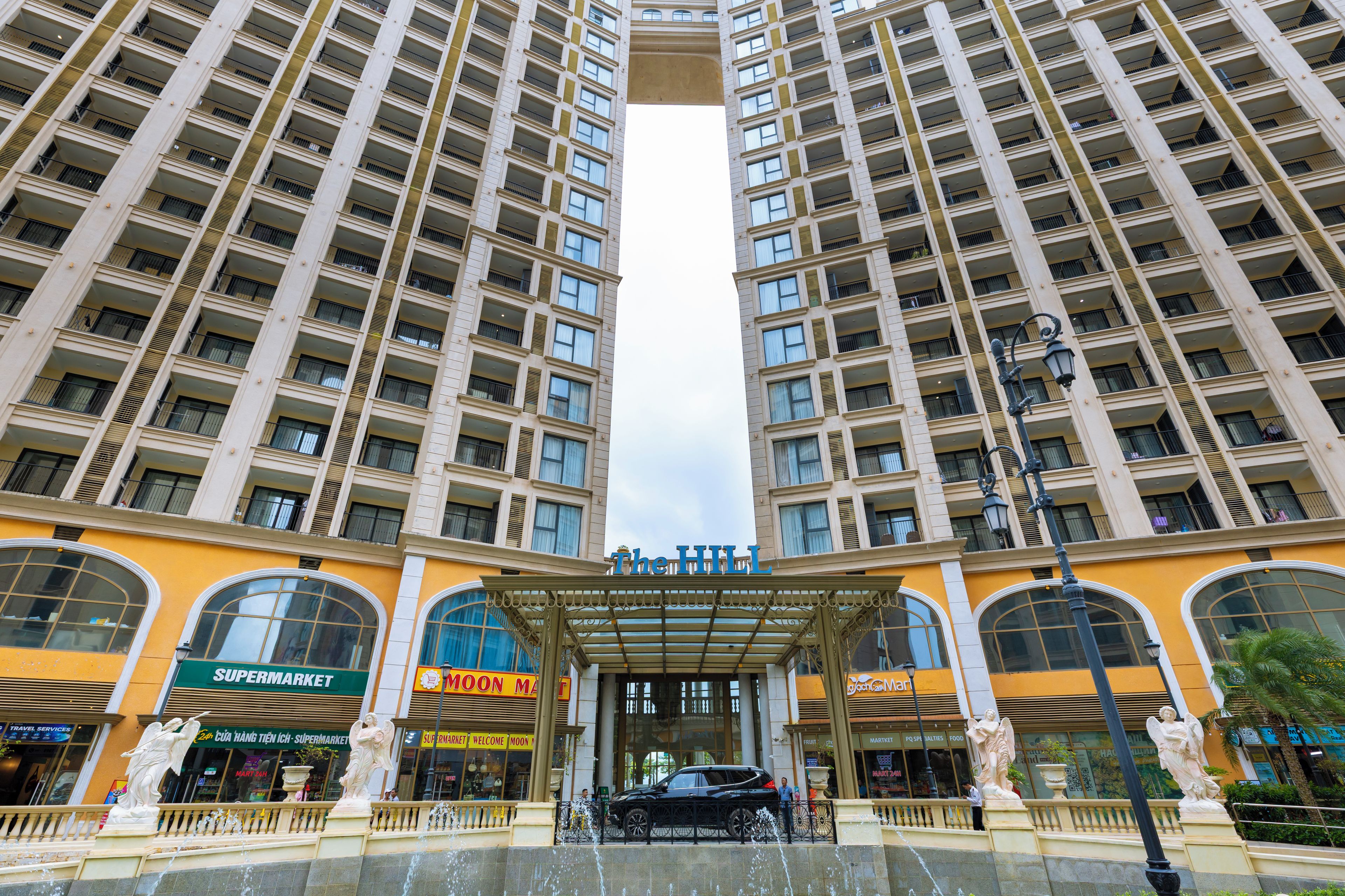 A high-rise hotel with multiple balconies, a central entrance with a canopy, and a fountain.