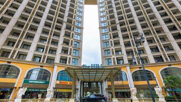 A high-rise hotel with multiple balconies, a central entrance with a canopy, and a fountain.