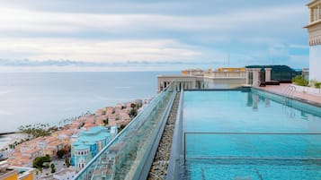 Una piscina a sfioro sul tetto con vista sull'oceano e sugli edifici costieri.