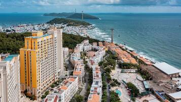 A coastal cityscape with a prominent yellow building, a marina, and a view of the sea.