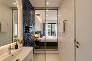 A modern bathroom with a shower, a sink, and a mirror. - Rei Gallery Appartments Hillside (Phu Quoc)
