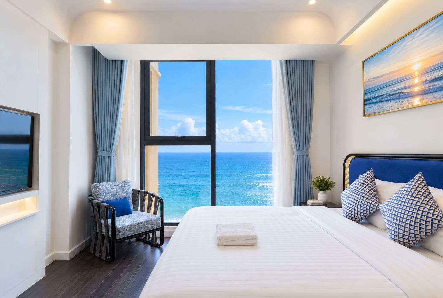 A hotel room with a large bed, a chair, a view of the ocean, and a painting on the wall.