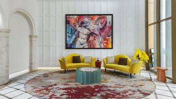 A room with two yellow sofas, a large abstract painting, and a patterned rug.