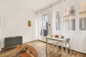 A dining area with a round table, chairs, and a radiator. - Cute & Cozy Studio in Paris 11th (Paris)