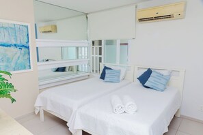 Une chambre d’hôtel avec un lit, une fenêtre, un miroir et un appareil de climatisation.