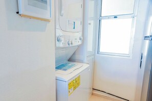 A laundry area with a washing machine, dryer, and a window. - Beachfront Cancun Condo · Ocean View · Pool & Private Beach (Cancún)