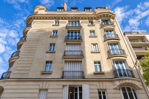 Ein mehrstöckiges Gebäude im klassischen Stil, mit Balkonen und schmiedeeisernen Geländern sowie einer symmetrischen Fassade.