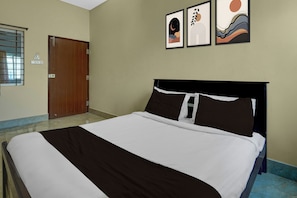 Habitació d'hotel amb un llit, una porta i tres quadres emmarcats a la paret.