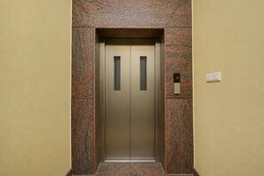Un ascensor amb acabat metàl·lic, flanquejat per parets amb un relleu decoratiu.