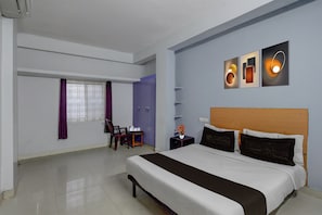 A hotel room with a large bed, a desk with a chair, a window with curtains, and wall-mounted artwork. - Super Hotel O Mallapur Crossway (Hyderabad)