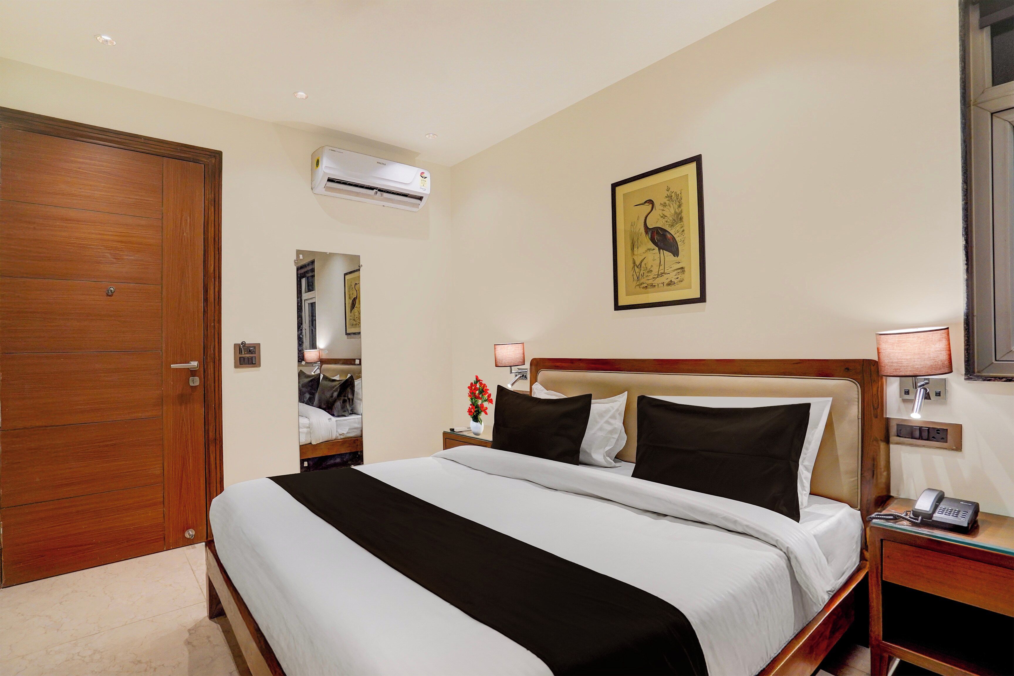 Une chambre d’hôtel équipée d’un lit, d’une table de chevet, d’une lampe et d’un appareil de climatisation.
