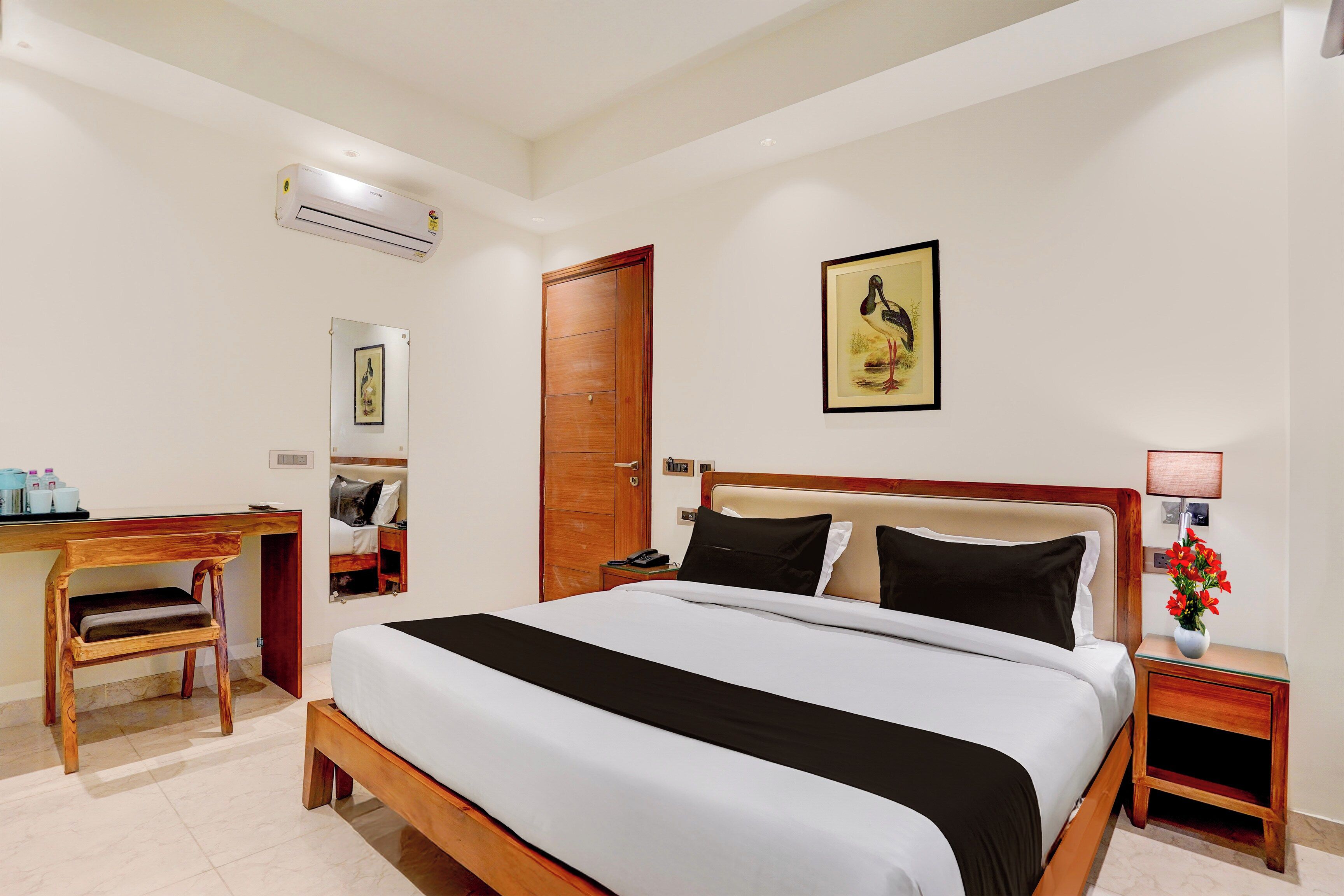 Habitación de hotel con cama, mesita de noche, lámpara y escritorio con silla.