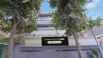 Un edificio residencial con un letrero que indica 'TOWNHOUSE OAK' y servicios 'OYO-Serviced'.