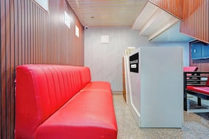 Una habitación con un sofá rojo, un refrigerador blanco y una pared a rayas.