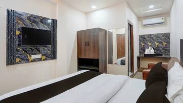 Una habitación de hotel con una cama, un armario, un televisor montado en la pared y un baño visible a través de una puerta abierta.