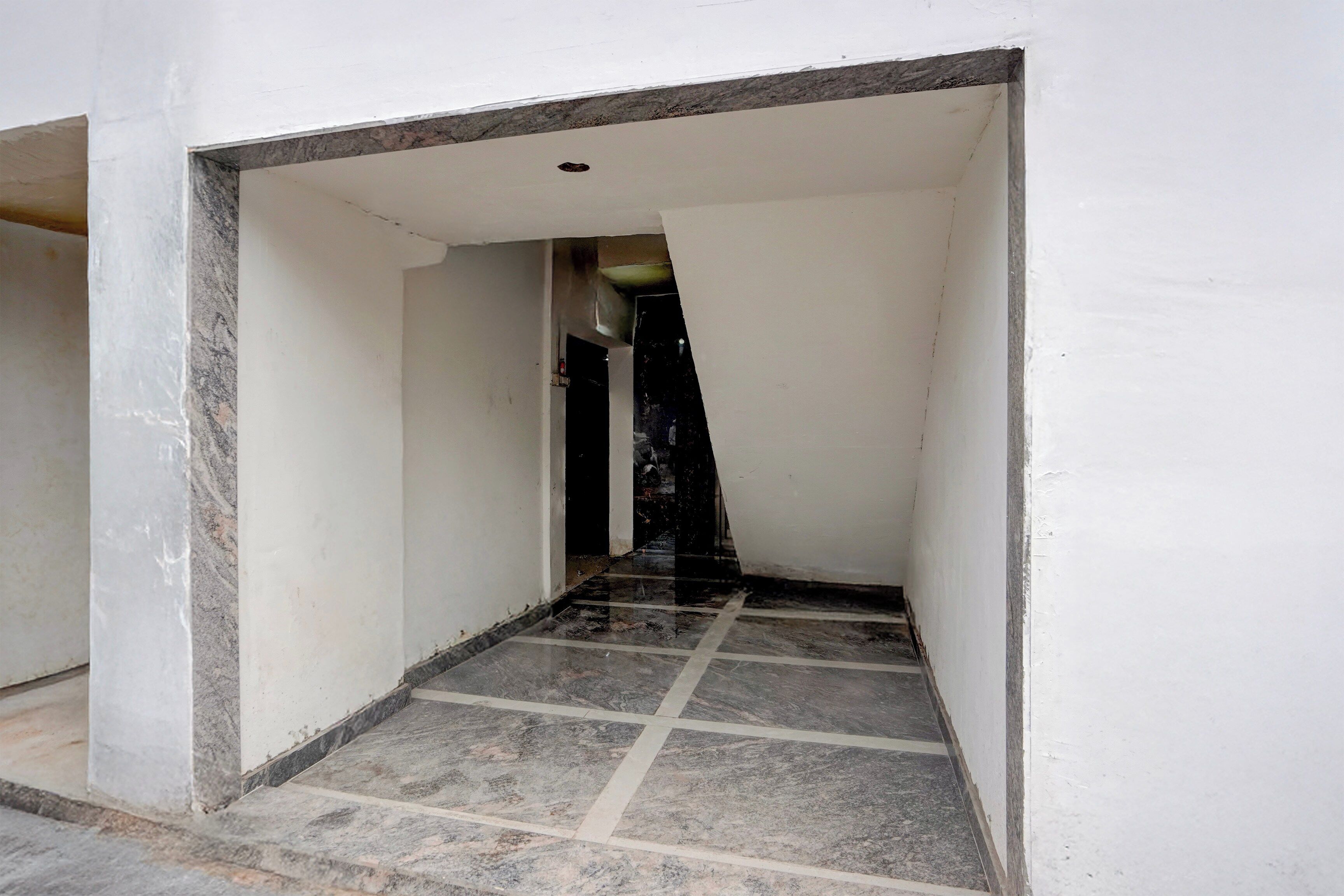 A narrow hallway with a tiled floor leading to a dark interior.
