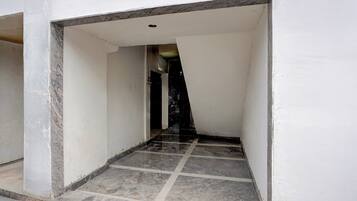 A narrow hallway with a tiled floor leading to a dark interior.