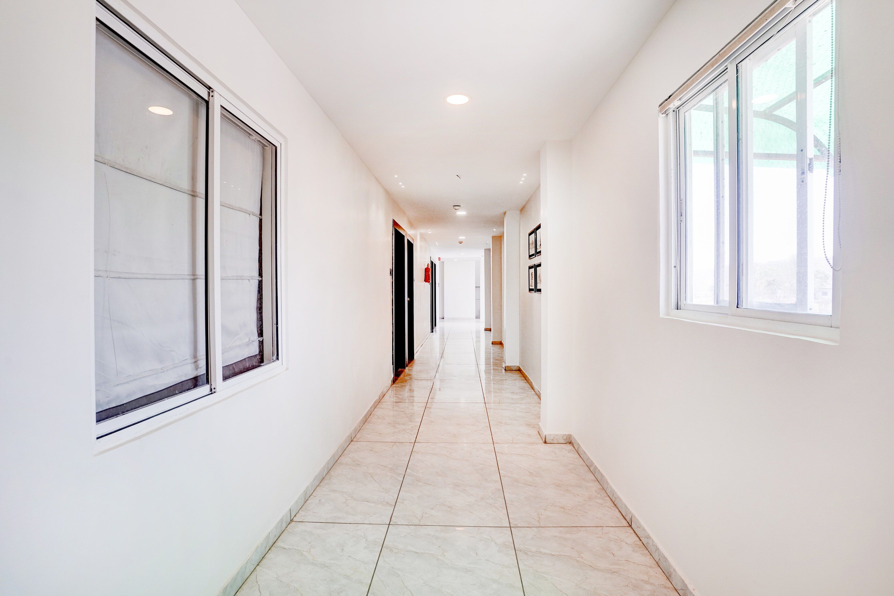 A corridor with large windows on both sides, leading to a door at the end.