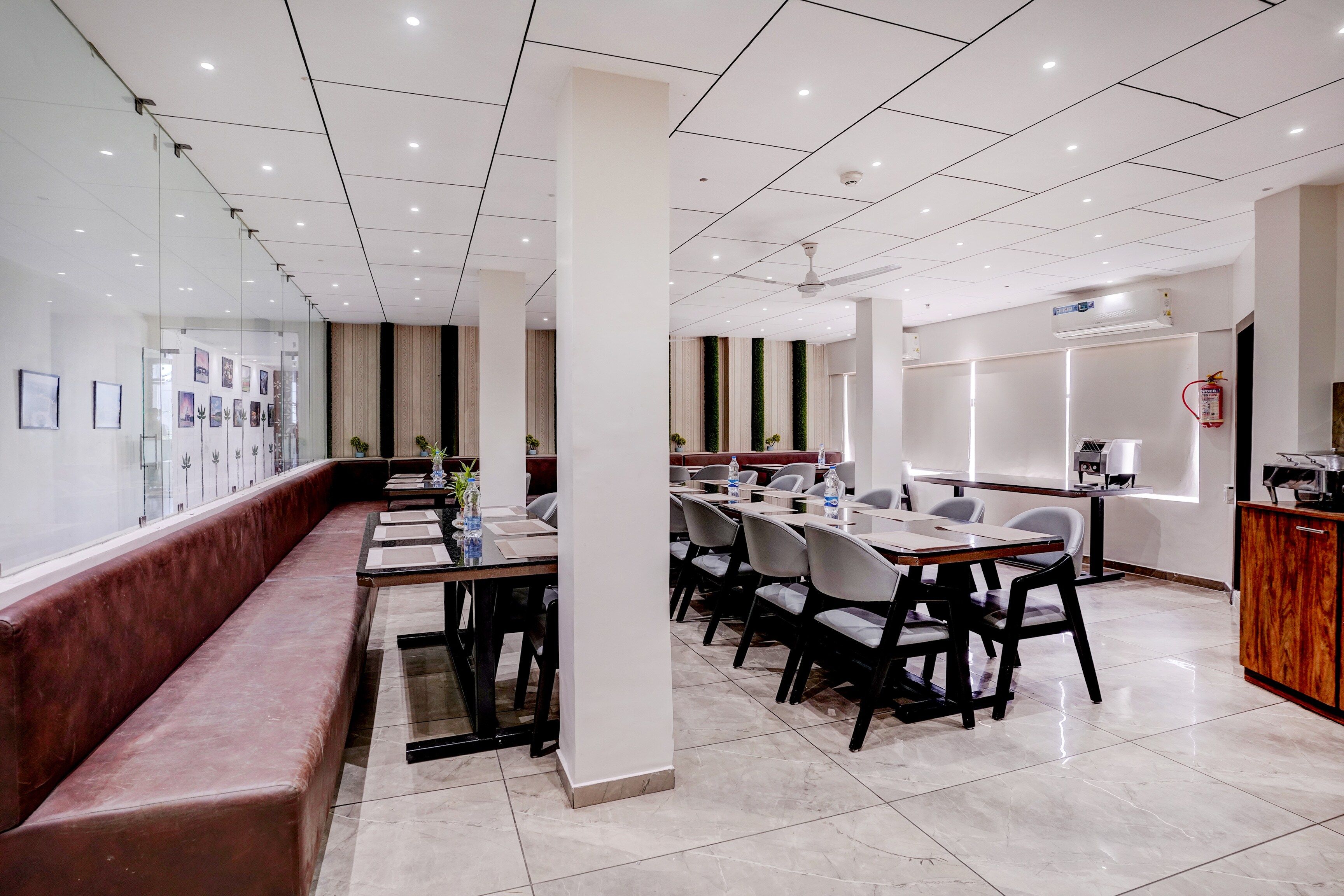 A modern dining area with a long bench, tables, and chairs.