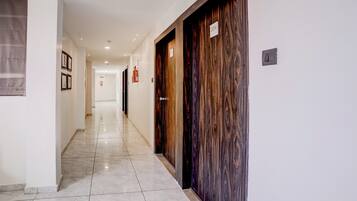 A hotel corridor with marble flooring, wooden doors, and framed pictures on the wall.