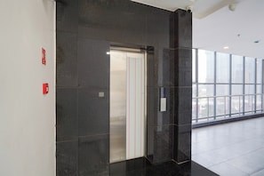A modern elevator in a building with a glass facade, emergency exit sign, and a clean, tiled floor. - Super OYO Townhouse Deva Road Lucknow (Lucknow)