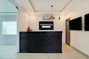 A reception desk with a black panel, a mounted television, and a ceiling light fixture. - Super OYO Townhouse Deva Road Lucknow (Lucknow)