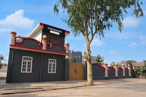 Una casa adosada con un letrero que indica que ofrece servicios para empresas, una entrada con reja y un árbol en primer plano.