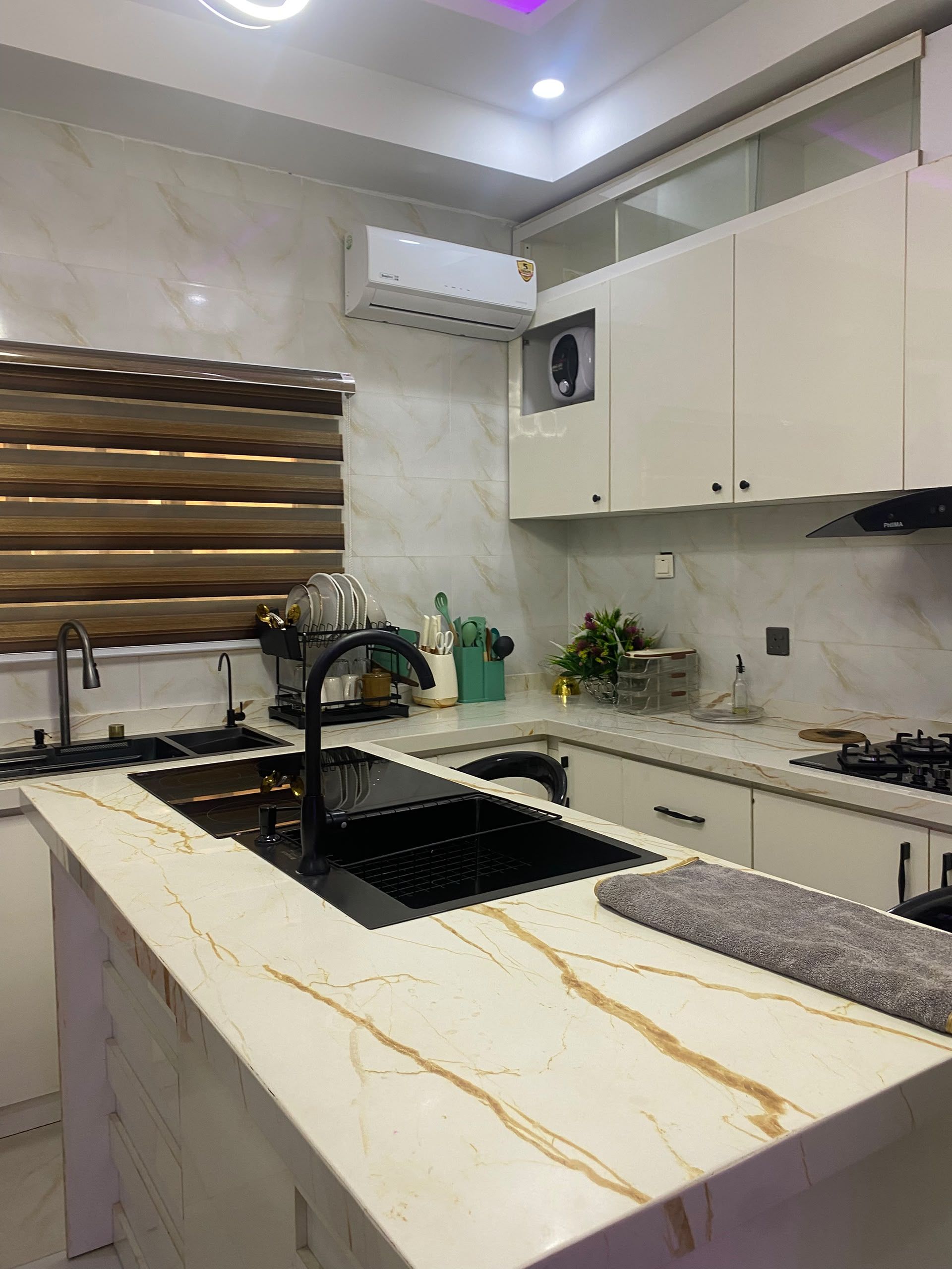 A modern kitchen with a marble countertop, black sink, and stainless steel appliances.