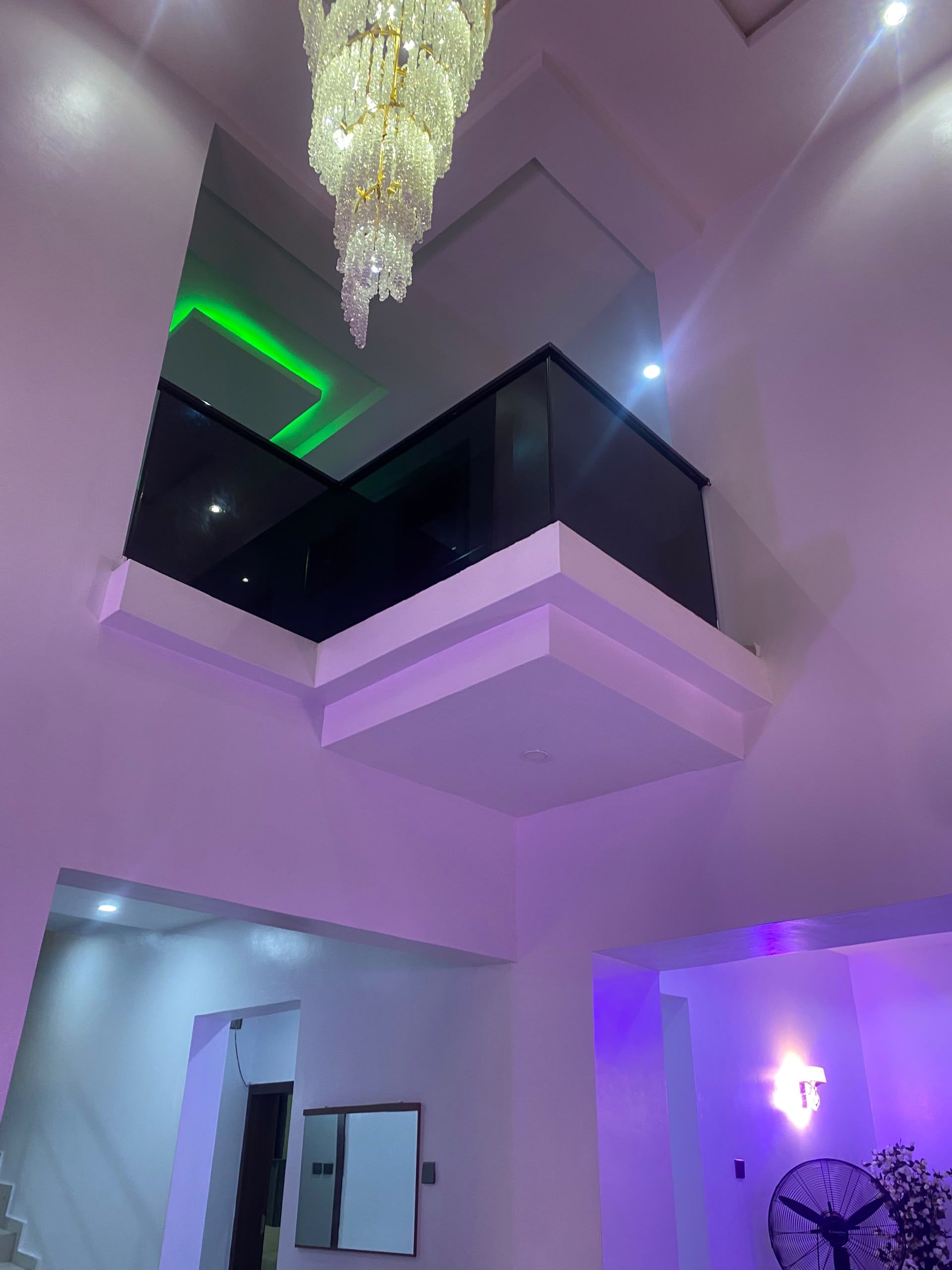 A modern interior with a balcony, a chandelier, and a fan.