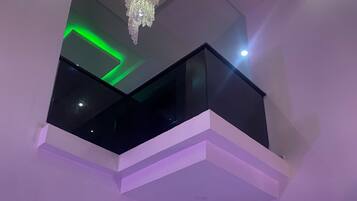 A modern interior with a balcony, a chandelier, and a fan.