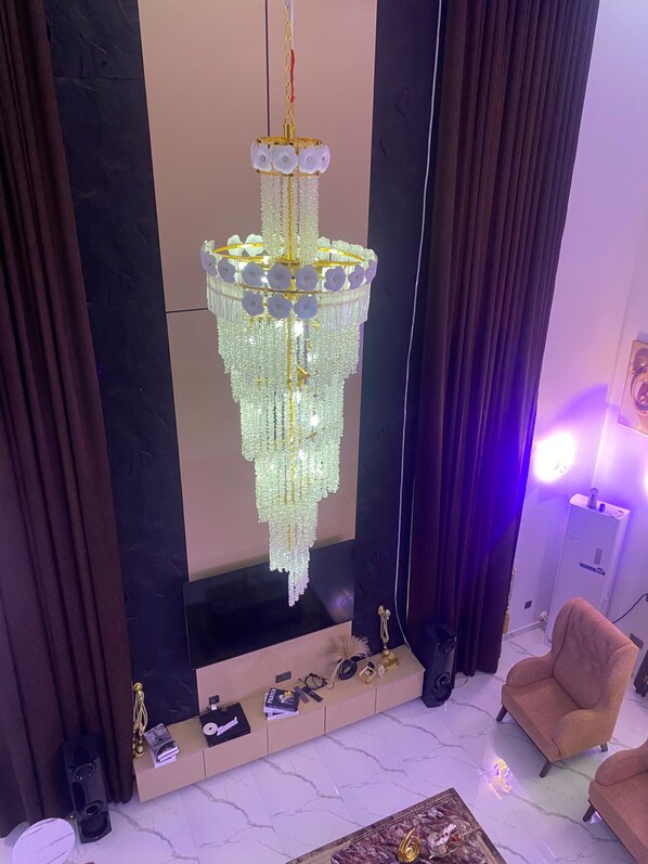 Un lustre à plusieurs niveaux, orné de cristaux pendants, un sol en marbre, un canapé et une console sur laquelle sont disposés divers objets.