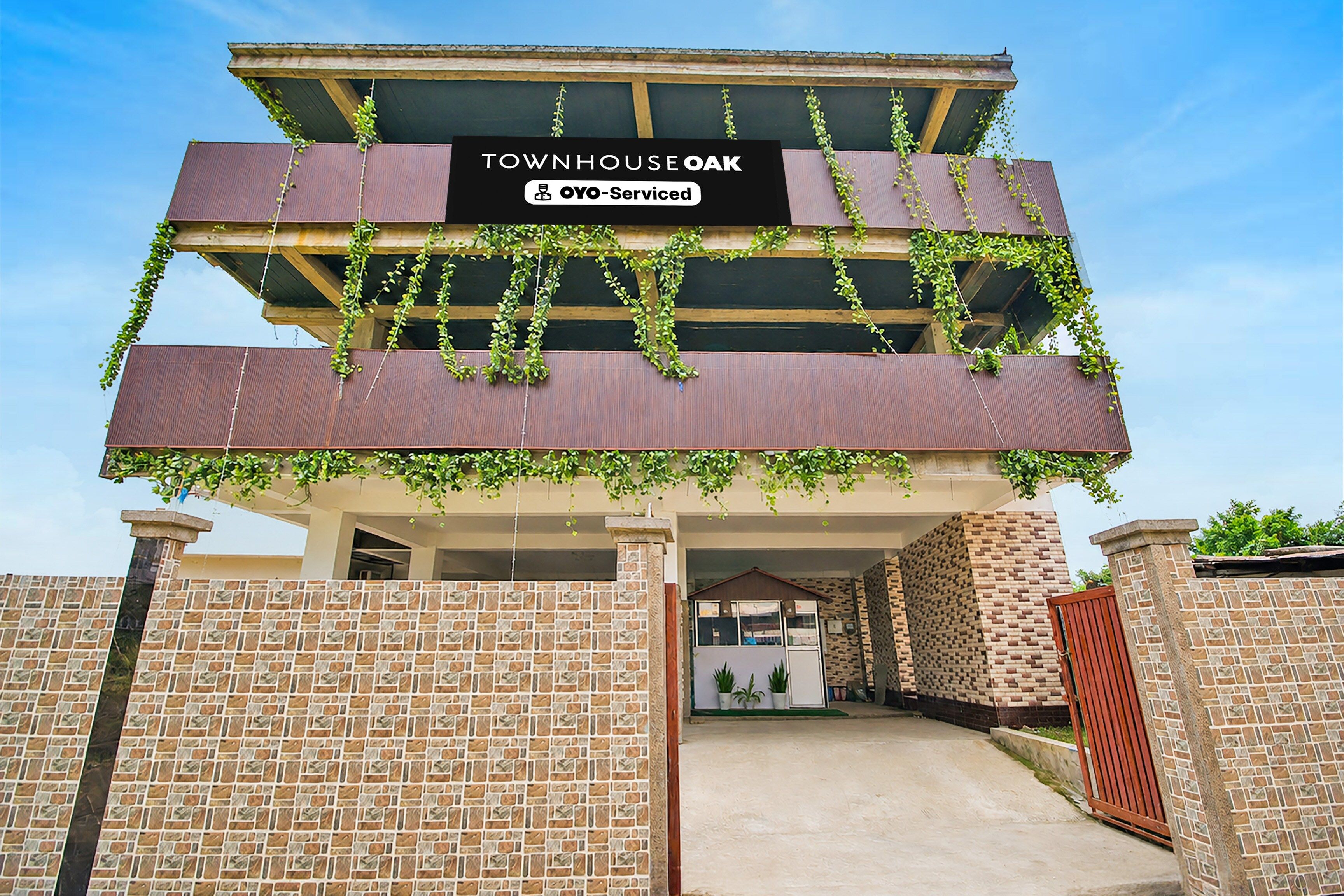 Un edificio de dos pisos con un letrero que dice 'TOWNHOUSE OAK' y 'OYO-Serviced'.