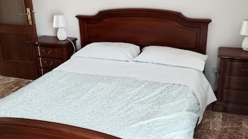 Un lit en bois avec une tête de lit, deux tables de chevet avec des lampes et une couvre-lit à motifs.