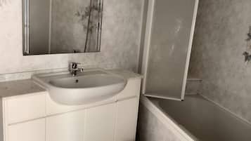 Une salle de bain avec un lavabo blanc, un miroir et une douche.