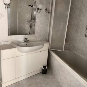Un bagno con lavandino bianco, specchio e doccia.