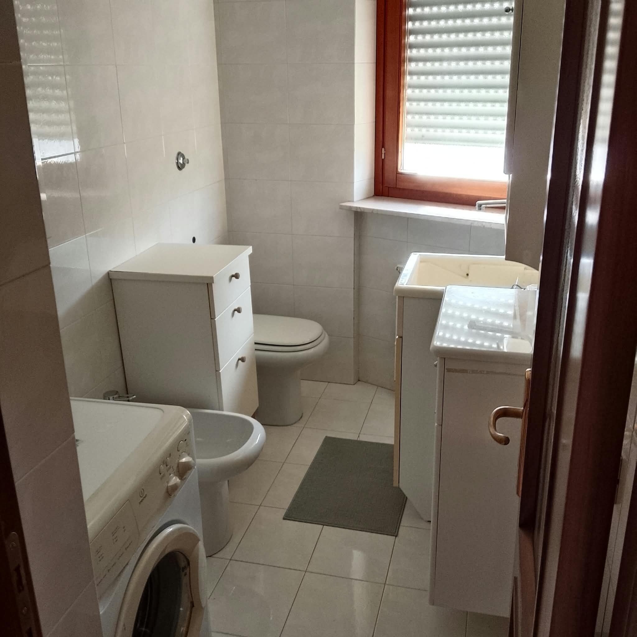 Ein kleines Badezimmer mit Toilette, Waschmaschine und Waschbecken.