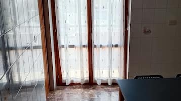 Une pièce avec un sol carrelé, une table et une fenêtre avec des rideaux.