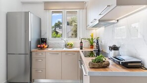 Una cocina moderna con refrigerador empotrado, cafetera y lavabo.