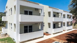 A modern multi-story residential building with balconies, a flat roof, and a clear sky. - Maria Ground Floor - Miralis Apartments (Episkopos)