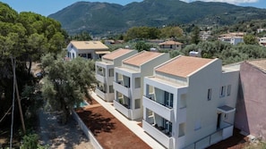 Zona residencial com edifícios modernos, céu claro e montanhas ao fundo.