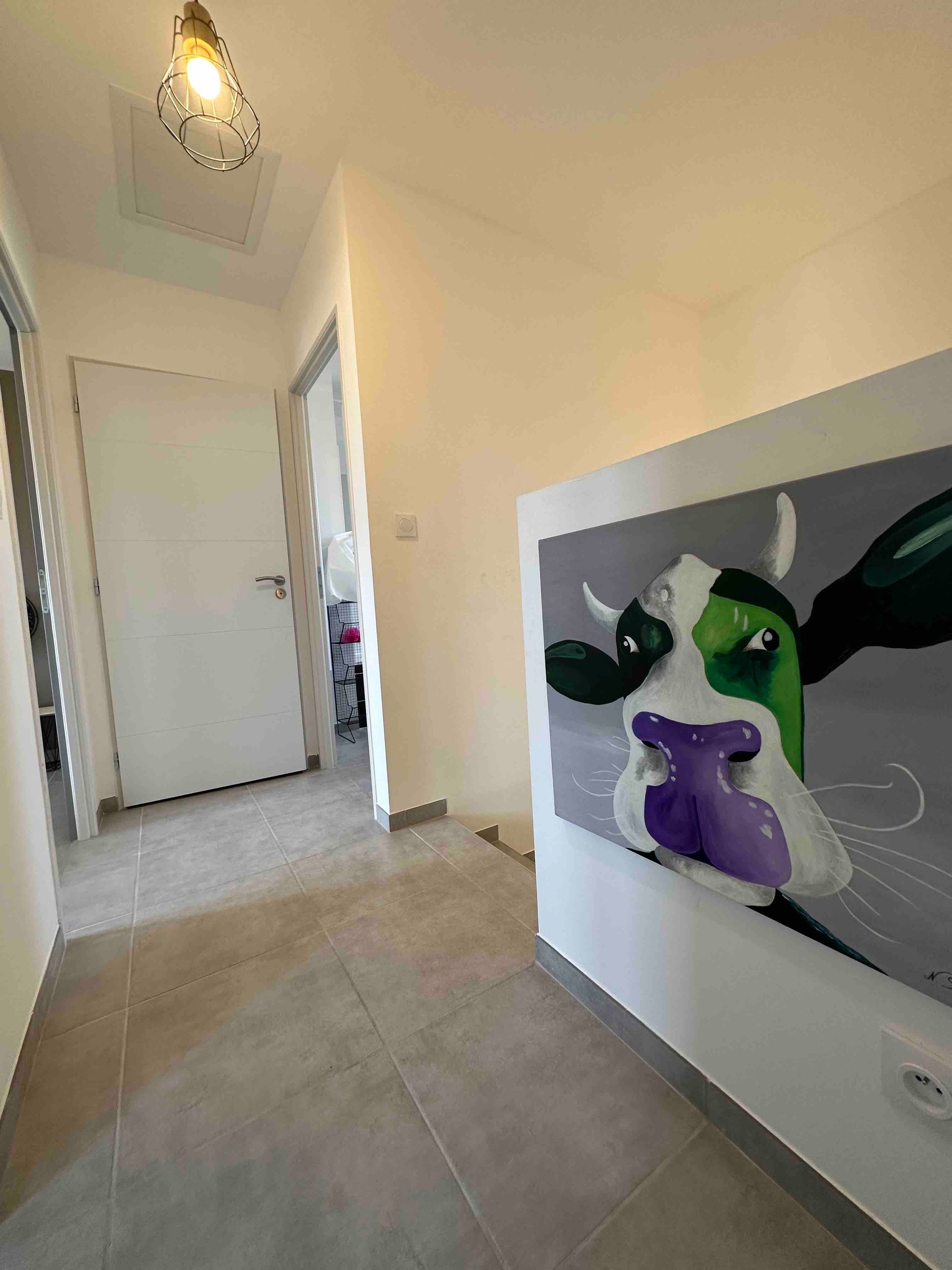 Ein Flur mit einer modernen Leuchte, einer Tür und einem Wandbild von einem Stier.