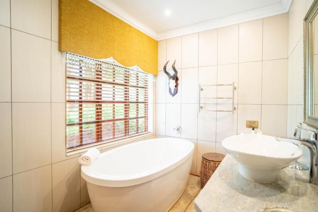 A bathroom with a bathtub, a sink, and a window with blinds.