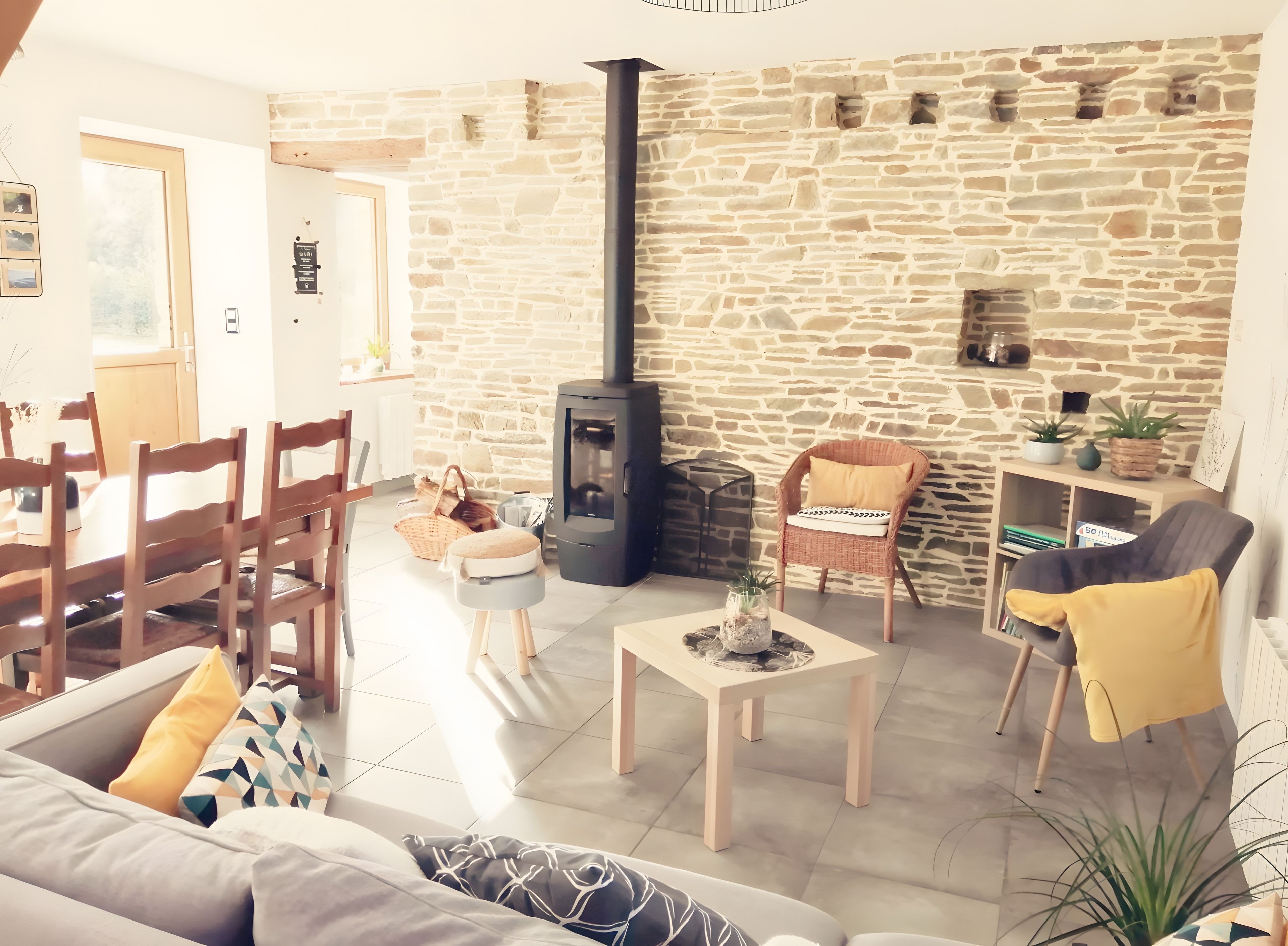 A cozy living room with a stone wall, a fireplace, a dining area with wooden furniture, and a comfortable seating arrangement.