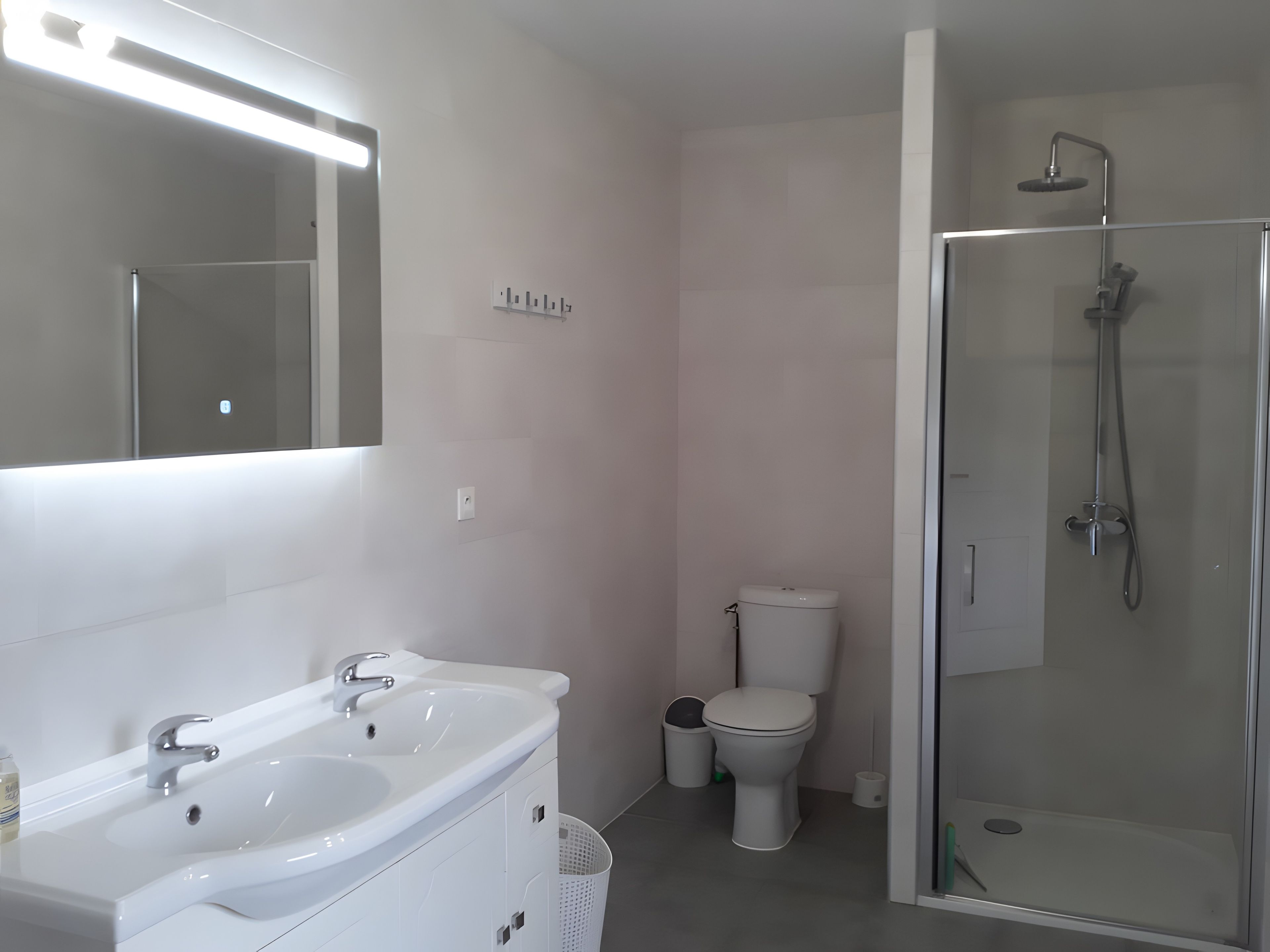 A modern bathroom with a white sink, mirror, and glass-enclosed shower.