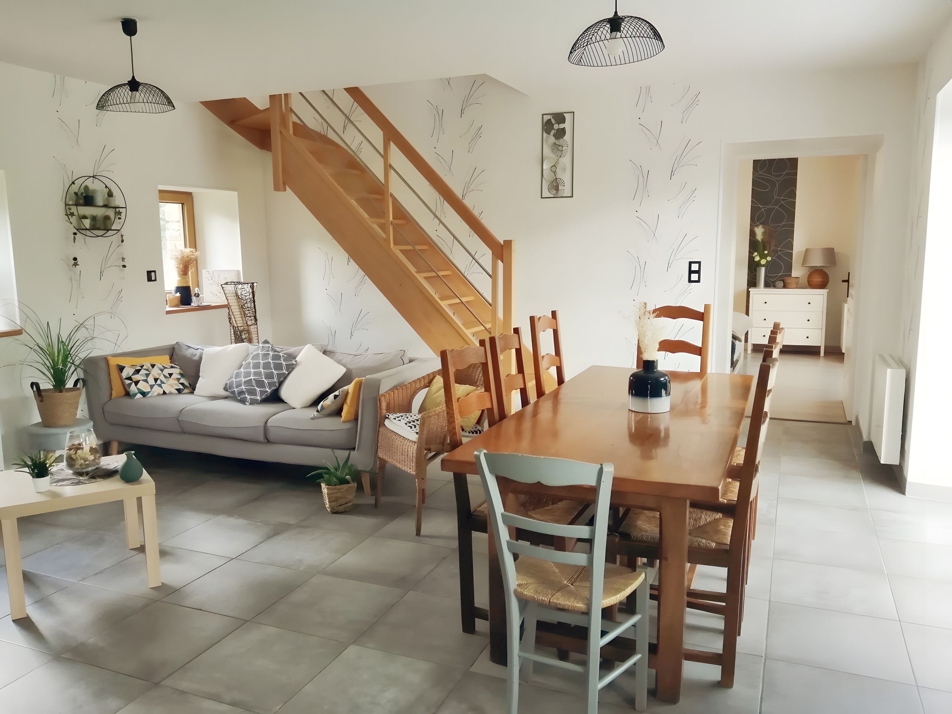 Een ruime woonkamer met een eettafel, bank en trap.