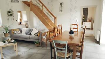 Een ruime woonkamer met een eettafel, bank en trap.