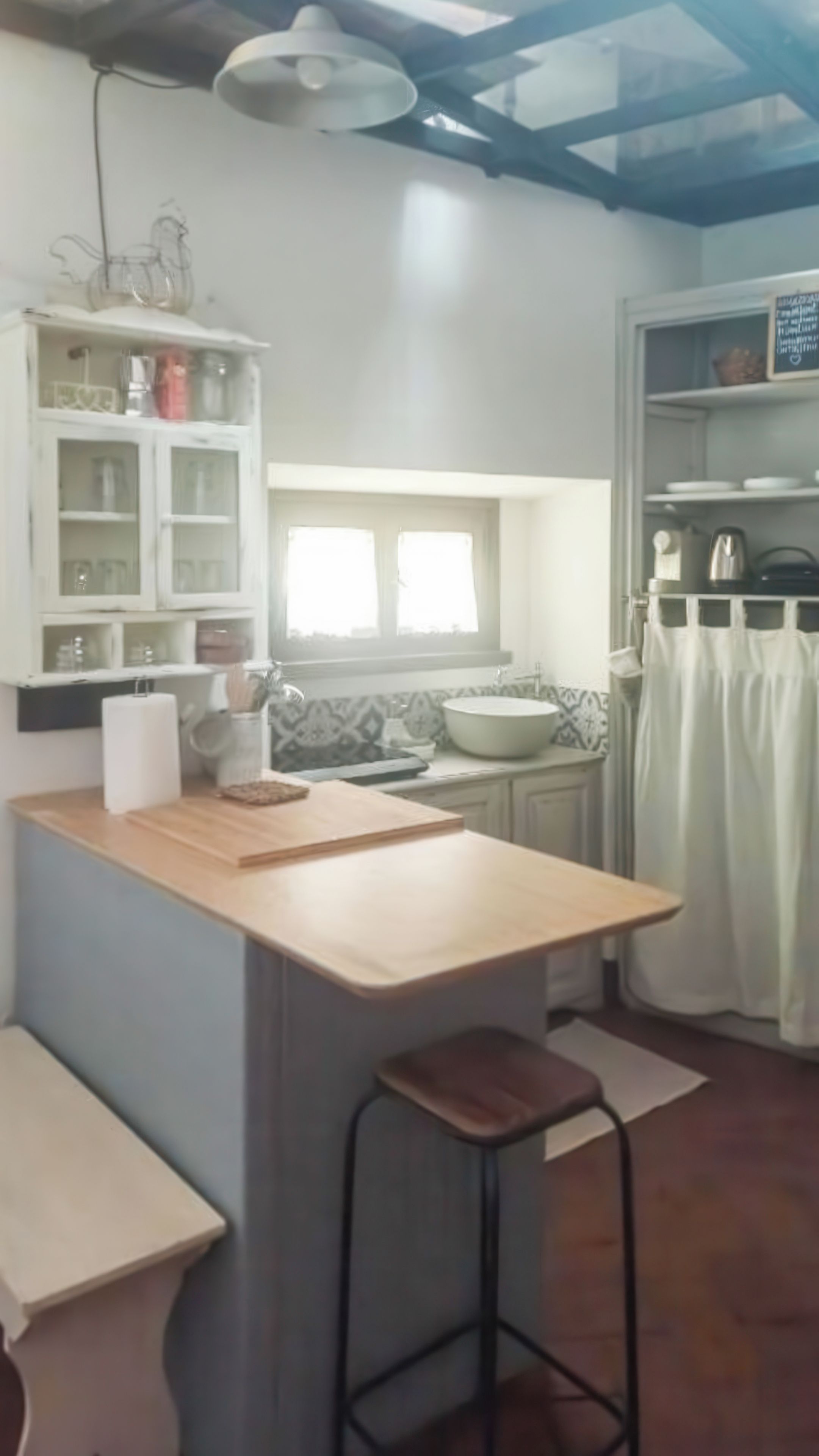 Une cuisine dotée d’un îlot central, d’une fenêtre au-dessus de l’évier et d’un meuble blanc aux portes en verre.